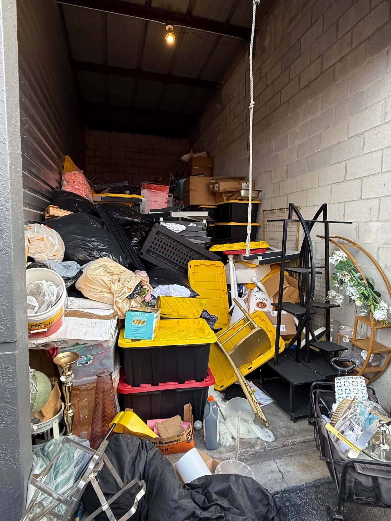 Before: a storage unit packed with bins, bags, shelving and decor
