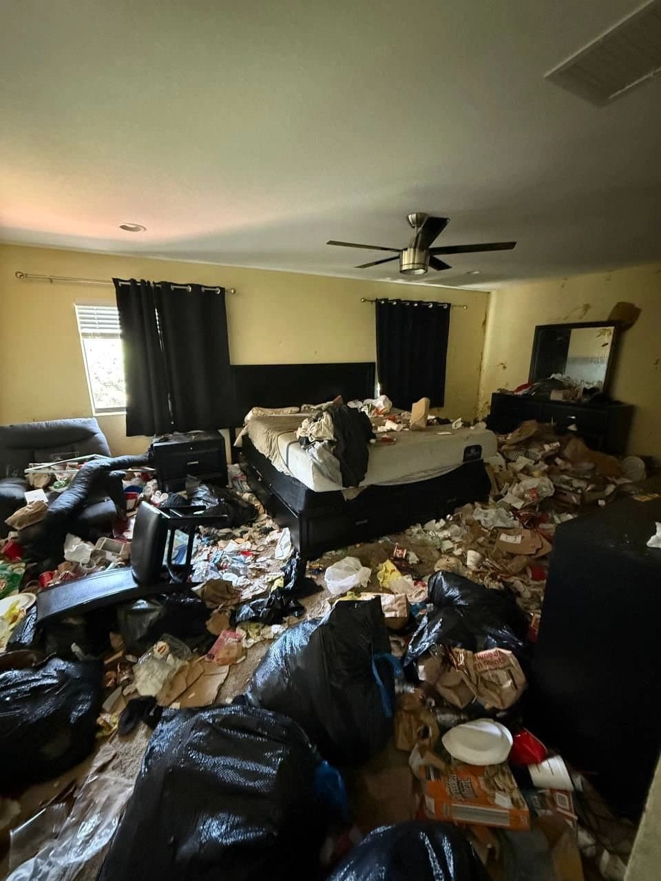 Bedroom buried in bags and debris before a cleanout