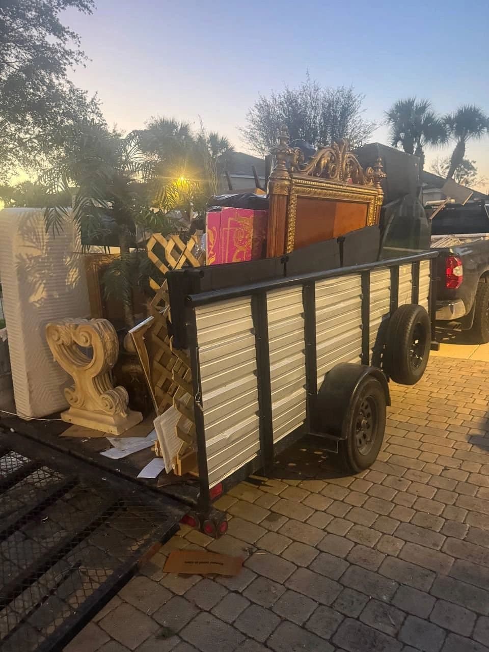 Tráiler cargado con una cabecera, un colchón y muebles de una recogida al atardecer